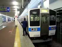 Serie 411/415: Ein neuerer Zug mit Wagen aus rostfreiem Stahl in Hakata (Stadt Fukuoka). Endwagen KUHA 411-1610. Der Schaffner zählt offenbar die Sekunden bis zur Abfahrt! 28.November 2010.