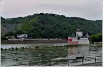 - UNESCO Welterbe Oberes Mittelrheintal - Bei Nieselregen f�hrt am 25.06.2011 einer der seltenen Z�ge auf der linken Rheinstrecke an der Burg Palzgrafenstein vorbei. Diese Burg, auch Die Pfalz bei Kaub genannt, wurde von dem Pfalzgraf bei Rhein im Rhein bei Kaub als Zollwache errichtet, um ein �berfahren der gegen�ber gelegenen rechtsrheinischen Zollstelle in Kaub zu verhindern. Wegen dieser Zweckbestimmung hat die Burg anders als andere Burgen am Mittelrhein nie Wohnzwecken gedient. Sie entstand im Laufe der Jahre aus einem von Ludwig dem Bayern 1326 bis 1327 errichteten Turm. Pfalzgrafenstein geh�rt neben der Marksburg und der Burg Boppard zu den wenigen nie zerst�rten Burgen im Oberen Mittelrheintal. Hinzu kommt, dass die Anlage nie stark ver�ndert wurde, und vor allem ist hier durch dendrochronologische Untersuchungen eine exakte zeitliche Datierung m�glich. Erst 1867, nachdem beide Rheinseiten preu�isch geworden waren, verlie�en die letzten Zollbeamten die Insel. (Jeanny)
