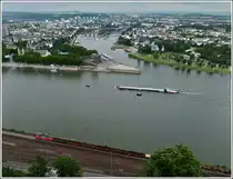 - An Mosel und Rhein - Die Stadt Koblenz mit dem Deutschen Eck bietet eine sch�ne Kulisse f�r die Rheinseilbahn und den G�terzug, welcher den Bahnhof Koblenz-Ehrenbreitstein am 24.06.2011 gerade erreicht. Das Deutsche Eck ist das Wahrzeichen der Stadt Koblenz und ein bedeutender Anziehungspunkt f�r Touristen. Seit 2002 ist das Deutsche Eck Teil des UNESCO-Welterbes Oberes Mittelrheintal, des Weiteren ist es ein gesch�tztes Kulturgut nach der Haager Konvention Das Deutsche Eck ist eine k�nstlich aufgesch�ttete Landzunge an der M�ndung der Mosel in den Rhein. Im Jahr 1897 wurde hier ein monumentales Reiterstandbild des Deutschen Kaisers Wilhelm I. errichtet, das als Denkmal f�r die Deutsche Reichsgr�ndung 1871 konzipiert war. Der Sockel des im Zweiten Weltkrieg schwer besch�digten Standbildes diente von 1953 bis 1990 als Mahnmal der Deutschen Einheit. Eine Nachbildung der Skulpturengruppe wurde 1993 nach vorausgegangenen kontroversen Diskussionen wieder auf dem Sockel angebracht. Zur Bundesgartenschau 2011 erfuhren die auf das Deutsche Eck zulaufenden Rhein- und Moselpromenaden umfangreiche Modernisierungsma�nahmen. Der Sockel des Reiterstandbildes musste 2009 ebenfalls wegen Sch�den saniert werden. Der Vorplatz des Denkmals wurde zur Bundesgartenschau erneuert, er bleibt aber w�hrend der Veranstaltung frei zug�nglich. Nahe dem Denkmal befindet sich die Talstation der als Attraktion zur Bundesgartenschau errichteten Rheinseilbahn, Deutschlands gr��ter Seilbahn. (Jeanny)