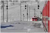 Endlich ist er da, der Schnee. Nur liegt er nicht immer dort, wo er sein sollte. Durch den eisigen Nordwind wurde das Gleis 2 in Ospizio Bernina 2253m zugeweht. Dank eines kirchlichen Feiertages in Italien, verkehrte ab dort ein Entlastungszug nach St.Moritz, sodass es um halb zw�lf zur ersten Zugskreuzung im h�chsten Bahnhof der RhB kam. Fast wie bei Tom Leitners Nebelbildern, war ich am richtigen Ort. BerninaExpress 1625 mit ABe 4/4 III 55  Diavolezza  und 51  Poschiavo  n�hert sich Ospizio Bernina. (08.12.2011)