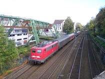 110 201 ist am 21.10.04 mit einem Zug der Linie RB 48 in Wuppertal-Oberbarmen neben der ber�hmten Schwebebahn unterwegs. Am Ende des Zuges l�uft eine 111er abgeb�gelt mit.