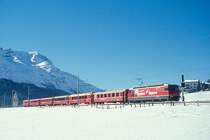 RhB Schnellzug 540 von St.Moritz nach Chur am 26.02.1998 bei Celerina mit E-Lok Ge 4/4III 641 - A 1263 - A 1283 - B 2493 - B 2379 - B 2360 - D 4223. Hinweis: Lok mit Werbung: Bernina-Express, gescanntes Dia
