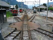 Bahnhof Meiringen 2005. Wo heute Autos stehen war vor wenigen Jahren noch eine sch�ne kleine Drehscheibe mit dazugeh�renden Abstellgleisen zu sehen. Statt den zwei Schotterwagen stehen heute zwei gedeckte G�terwagen am G�terschuppen. (23.07.2005)