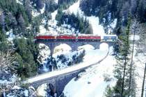 RhB G�terzug 5346 von Pontresina nach Landquart am 03.03.1996 auf Albula I-Viadukt zwischen Preda und Muot mit E-Lok Ge 4/4II 617 - Ge 4/4II 632 - Ge 6/6II 705[geschleppt] - Gbkv - 2x Haikv - Rw - Gakv - Gbkv - Lb - Rw - 2x Gbkv. Hinweis: gut sichtbar die im Winter auf der Albula-Pa�stra�e eingerichtete gesicherte Schlittelbahn von Preda nach Berg�n, gescanntes Dia
