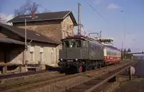Hasbergen bei Osnabr�ck an der Rollbahn.
Damals war die Osnabr�cker Museum Lok E 0420 noch einsatzbereit und wurde
z. B. wie an diesem Tag auch f�r �berf�hrungsfahrten benutzt. Am 9.3.1990
�berf�hrt sie den Rheingold Buckel Speisewagen in Richtung M�nster und
passiert gerade den Bahnhof Hasbergen. Damals stand ich allein auf dem
Bahnsteig und machte dieses Bild. Heute wird dieser Fotopunkt an manchen
Tagen von zahlreichen Fotografen aufgesucht, so dass es manchmal auf
diesem Bahnsteig Punkt eng werden kann.

Der links erkennbar beginnende Anbau des G�terschuppen wurde �brigens
ca. 2008 entfernt und der Bahnhof wurde hervorragend restauriert. Er steht
heute in privater Nutzung.

Die alte E 0420, 1934 bei AEG in Berlin gebaut, wurde nach einem Unfallschaden nicht wieder repariert. Man stellte sie �u�erlich konserviert zusammen mit einem
Mitropa Speisewagen an der Zentrale der DB in Frankfurt als Denkmal auf.
