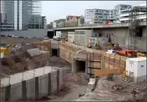 . Zwei Tunnelröhren für die Linie U12 - 

Für die U12 (zukünftig Dürrlewang - Hauptbahnhof - Hallschlag - Remseck) werden nahe des Stuttgarter Hauptbahnhofes zwei Tunnelröhren gebaut. Die links im Bild schon im Rohbau fertigen Tunnels wurde schon vorab mit dem Bau der neuen Stadtbibliothek mitgebaut. Nun geht es in Richtung Hauptbahnhof weiter. Die beiden Tunnelröhren treffen auf die ebenfalls neu zu bauende Tunnelröhren der Linien U5, U6, U7 und U15. Diese Tunnelröhren müssen neu gebaut werden, da der bestehende Tunnel der Talquerlinien ins Lichtraumprofil der zukünftigen Bahnanlagen von Stuttgart 21 hineinragen würde. Der neue Stadtbahntunnel liegt tiefer und wird unter der Bebauung bergmännisch errichtet. Der jetzige Stadtbahntunnel liegt unter der Heilbronner Straße (B 27), im Bild hinter der Betonwand. Die U12-Strecke wird an den neuen Tunnel kreuzungsfrei angeschlossen. Auf der anderen Seite der Stadtbibliothek kommt die U12 über eine ebenfalls im Rohbau schon fertige Rampe ans Tageslicht und erhält auf einem Brückenbauwerk eine Station zur Erschließung des Neubaugebietes in diesem Areal (früher befand sich hier der Güterbahnhof). Kurz vor der Haltestelle  Milchhof  erreicht die U12 dann die bestehende Strecke der U15. 

04.04.2013 (M) 