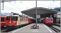 Zwei Japaner in Disentis/Must�r. Ge 4/4 II 622  Arosa  mit Anschrift der RhB-Schwesterbahn Hakone Tozan Railway und HGe 4/4 5  Mount Fuji  der MGB. (04.04.2013)