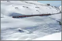 Blick von der Passstrasse auf den BerninaExpress 972 mit den ABe 4/4 III 55  Diavolezza  und 54  Hakone . Der BEX972 hat soeben die Station Ospizio Bernina verlassen und f�hrt entlang des halbleeren Lago Bianco Richtung St.Moritz. (18.04.2013)