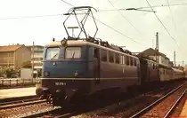 110 178-1 und eine abgebügelte 144 vor einem Nahverkehrzug im Mai 1978 im Bahnhof Reutlingen. Zwar fast eine Gegenlichtaufnahme, aber die Lok befindet sich noch weitgehend im Originalzustand ohne DB-Logo, dafür hat sie noch die Stirnlampen mit integriertem Rotlicht und eine große Dachleuchte, einen weißen Zierstreifen zwischen Rahmen und Aufbau, Regenrinne, umlaufende Griffstange, Trittrost, Lamellen-Lüftungsgitter und Maschinenraumfenster zum Öffnen.   