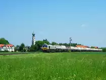 Eine Class 66 f�hrt am 15.05.2012 mit ihrem Kesselwagenzug aus Richtung Burghausen kommend am Kirchturm von Heiligenstatt vorbei.