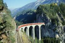RhB Schnellzug 560 von St.Moritz nach Chur am 24.10.1997 auf Landwasser-Viadukt zwischen Filisur und Alvaneu mit E-Lok Ge 4/4 III 645 - B 2444 - AB 1522 - A 1226 - B 2392 - B 2357 - B 2376 - D 4221 - Z 13091. Hinweis: diese ber�hmte Fotostelle bietet Ende Oktober nur kurze Zeit gute Lichtverh�ltnisse. Aufnahme entstand ca. 15:10h, wie zu erkennen ist, liegt die Felswand noch im Schatten! Aber der Viadukt ist bereits wieder im Vollschatten zur Sommerzeit ab ca. 17:10h, zur Winterzeit vor 16:10h. Gute Fotos mit Planschnellz�ge Richtung Chur sind nur 1 oder 2 Aufnahmen m�glich! gescanntes Dia.
