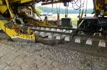 Schotterbettreinugungsmaschine von Plasser&Theurer im Einsatz, unter dem angehobenen Schienenstrag entfernt eine umlaufende Baggerkette den alten Schotter und bef�rdert ihn zum dahinterliegenden Reinigungswagen, BSB-Strecke Gottenheim-Hugstetten, Aug.2013