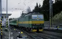 Strba am Fu� der Hohen Tatra ist ein sehr interessanter Bahnhof.
Im oberen Teil, innen im Bahnhof Geb�ude befindet sich die Talstation
der Zahnradbahn. Unten, quasi auf Ebene  Null  liegt der Bahnhof. Dieser
zieht sich in weitem Bogen durch zwei lang gestreckte Kurven. An den Zufahrten
und auch von der B�schung von oben herab kann man den Bahnhof wunderbar einsehen
und hat viele M�glichkeiten, sich einen Fotopunkt zu suchen. Am 3.5.2003 versuchte ich es in der �stlichen Zufahrt und fotografiere dort die slowakische 163244 mit ihrem Os aus Poprad bei der Einfahrt.