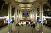 Plärrer, Linien U1/11, U2 (1980) -  

Diese viergleisige Umsteigestation hat übereinander liegende Bahnsteige für Richtungsbetrieb. Oben fahren die Bahnen stadtauswärts, auf den unteren beiden Gleisen stadteinwärts. Das Bild zeigt die großzügige räumliche Situation der oberen Bahnsteighalle auf der Ostseite, wo sich das Fußgängergeschoß galerieartig zum Bahnsteig öffnet und Tageslicht über runde Oberlichter auf den Bahnsteig fällt. Bei den später gebauten Bahnhöfen wurde dieser offene Übergang zwischen Fußgängergeschoß und Bahnsteig häufig angewandt, was der Enge unterirdischer Verkehrsanlagen entgegenwirkt und für mehr Übersichtlichkeit sorgt. Unter der tiefen Bahnsteigebene wurde in Ebene -4 schon die Möglichkeit einer hier L-förmig kreuzenden weiteren Linie vorbereitet. 

04.03.2006 (M)