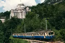 FART/SSIF: Personenzug mit dem ABDe 4/4 18 (1924) auf der Fahrt von Domodossola nach Locarno im Juni 1986. Die Aufnahme ist vor der Kulisse der bekannten  Wallfahrtskirche von Re entstanden. Die Wallfahrtskirche Madonna del Sangue mit dem Bildnis der blutenden Madonna (erinnert an das Wunder von 1494) gehört zu den interessantesten Sehenswürdigkeiten an der Strecke der Centovallibahn.
Foto: Walter Ruetsch