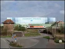 HVLE V490.1 rangiert am 11.04.2014 im Bahnhof Stralsund-Rügendamm vor der Kulisse der Volkswerft, über der auch an diesem Tag nicht nur symbolisch dicke Wolken hingen.