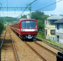 Die Fahrzeuge des Keihin Ky�k�-Konzerns, Serie 2000: 1982 bis 1987 gebaut f�r Reisen �ber weitere Distanzen, umlegbare bequeme Quersitze. Es gibt je 6 Vierwagen- und Achtwagenz�ge. Bild: Zug 2031 begegnet bei Zushi im Westen der Miura Halbinsel, 25.Juni 2011. (durch die verglaste F�hrerstandr�ckwand eines Gegenzugs). Serie 2000: 1435 mm Spur, Gleichstrom 1500 V. 6 Achtswagen- und 6 Vierwagenz�ge, erbaut 1982-1987. F�r Expressz�ge bestimmt, im Wageninneren haupts�chlich Sitzbankgruppen statt L�ngsb�nke. Sp�ter umgebaut mit einer zus�tzlichen Mittelt�re und L�ngsb�nken; einige der alten Sitzbankgruppen gingen an die Amerikanische Navy in Yokosuka f�r ihre Busse. Die Serie 2000 konnte nicht auf die U-Bahn (St�dtische U-Bahn, Asakusa Linie) einfahren, wie die meisten anderen Keiky�-Z�ge. Alle Z�ge wurden bis 2018 ausgemustert. 