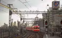 Die Fahrzeuge des Keihin Kyûkô-Konzerns, frühere Wagen: Zwischen 1959 und 1978 wurden 356 Wagen verschiedenster Varianten für Pendlerzüge in Dienst gestellt. Sie konnten auch auf der Städtischen U-Bahn Tokyo verkehren. Stets 2 Wagen bildeten eine Einheit. Die letzten Fahrzeuge dieses Typs schieden 2010 aus. Im Bild Einfahrt von Wagen 1020 (Serie 1000 Erste Generation, 1020 aus den Baujahren 1959-1960) in einem 4-Wagenzug in das damals erst im Entstehen begriffene Wirtschaftszentrum Tokyo-Shinagawa, 15.Februar 1980. 