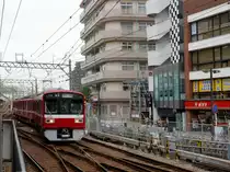 Zweiglinien des Keikyû-Konzerns - die Daishi-Linie: Einfahrt des Vierwagenzugs 1505 in den Bahnhof (Keikyû)-Kawasaki. Die gelbe Werbung am Geschäftshaus rechts weist darauf hin, dass man sich hier beraten kann bei Ueberschuldung und wenn man sich nicht aus dem Teufelskreis von Wucherzinsen zu befreien weiss (was besonders in dieser Gegend nicht selten ist). 24.Oktober 2011. Zur Serie 1500: 1435 mm Spur, Gleichstrom 1500 V. Erbaut 1985 - 1993. Anfänglich 4-, 6- und 8-Wagenzüge. Heute (2024) 2 Vierwagenzüge (1521 ff), 15 Sechswagenzüge (1529 ff), und 5 Achtwagenzüge (1707 ff).   