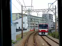 Zweiglinien des Keikyû-Konzerns - die Daishi-Linie (4,5km): Diese 1899 gebaute Linie war die erste elektrische Bahn Japans und auch die erste normalspurige Strecke. Sie diente als Zugang zum Kawasaki Daishi, den grossen buddhistischen Tempelanlagen von Kawasaki mit Strömen von Wallfahrern, die zur Erfüllung aller möglichen Wünsche zu diesem im 12.Jahrhundert gegründeten Zentrum pilgerten. Das Bild in der Nähe der Station Kawasaki Daishi zeigt allerdings, dass es sich heute um ein eher ärmliches Gebiet handelt mit Millionen von hässlichen und engen Wohnungen. Vierwagenzug 1501 (Serie 1500, 1985 gebaut) kommt entgegen. 24.Oktober 2011. (Durch die verglaste Führerstandrückwand eines Gegenzugs)  
