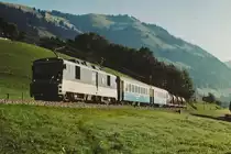 MOB: Zementverkehr Montreux-Saanen im Juli 2003. Die Zufuhren der beladenen Zementwagen ab Montreux sowie die Abfuhren des Leermaterials ab dem Bahnhof Saanen wurden jeweils den Regionalzügen mitgegeben. Das Rangiermanöver um Saanen wurde mit einem alten in Saanen stationierten Triebwagen abgewickelt. Regionalzug mit GDe 4/4 6001-6004 auf der Fahrt nach Montreux zwischen Rougemont und Flendruz.
Foto: Walter Ruetsch 