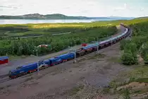 Der Ic 96 von Narvik kommend nach Stockholm,geführt von Lok Rc 6 1326 wird  umschlängelt  von einem vollem Erzzug,geführt von Björkliden 110 mit Lulea 103.Bild vom 20.7.2014 am Bahnhof Torne Träsk