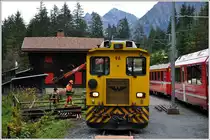 Der Unterhaltsdienst der RhB verlädt mit dem Kran des Tm 96 Schwellen in Cavadürli, währenddem RE1044 die Kreuzung mit RE1043 abwartet. (14.10.2014)