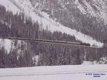 Reisezug f�hrt talw�rts �ber den Viadukt Albula 1 - M�rz 1979. Die Strecke (ganz unten im Bild) kommt rechts vom Zwondra-Tunnel, geht links �ber den Viadukt Albula 2 und einer Schleife am Gegenhang zum Viadukt Albula 1 und weiter nach rechts zum Toua-Tunnel.