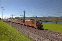 Re 425 180  Neuchatel  und die Re 425 167  Ausserberg  fahren mit einem langen Containerzug bei Reichenburg vorüber.Bild vom 22.4.2015