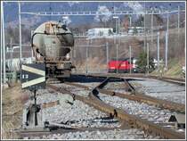 Braunkohlestaub-Wagen der VTG Hamburg mit deutschen Zugschlusssignalen in der �bergabegruppe der Holcim Zementwerke Untervaz. Ein Interregio mit Re 460 rauscht unter der RhB Br�cke hindurch Richtung Landquart. (09.02.2007)