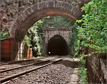 Die doppelten Tunnelportale der Schwarzwaldbahn sorgen immer wieder für Erstaunen. Das Portal des Eisenbergtunnels, Offenburger Seite, ist durch die Anlehnung an die Gothik eine besondere Schönheit. Auch zeugen die großen Felsbrocken im Gemäuer vom Originalzustand des Portals. Betrachtet man historische Aufnahmen, so scheinen die Mauern mit feineren Steinquardern neueren Datums zu sein. Niederwasser, August 2006.

Der Fotograf stand bei der Aufnahme gut überwacht deutlich neben den Gleisen. Auch bitte die Qualität entschuldigen, die Aufnahme entstand noch mit einer 3-MPx-Kamera.