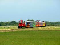 Kurz vor dem Anleger ist dieser Zug der Langeooger Inselbahn am 25.07.2015 unterwegs.