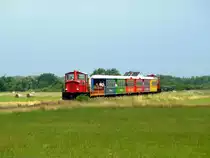 Kurz vor dem Anleger ist dieser Zug der Langeooger Inselbahn am 25.07.2015 unterwegs.