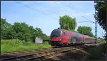 Hier ist der Railjet aus Budapest auf freier Strecke zu sehen. Er passiert gerade den Bahnübergang zwischen Komárom und Ács auf der ungarischen Kbs 1.Szenario vom 01.August 2015.