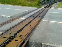 Hier zu sehen ist der DFB-Bahnübergang  Bogen  bei km 41.515 (nahe des Bahnhofs Oberwald) am 22.7.2015. Dieser Bahnübergang ist wohl durch seine absenkbare Zahnstange einzigartig. Während der Winterpause wird die Zahnstange zum Schutz vor Korrosion und Beschädigung ausgebaut und die Lücke durch eine Ersatzkonstruktion geschlossen. Die Konstruktion wurde am 6. Mai 2010 als Element mit einem Gewicht von 135 Tonnen in die Straße eingebaut. Die Wiederinbetriebnahme der gesamten Bergstrecke erfolgte am 12 August 2010.

Funktion: Die drei Zahnstangensegmente werden über Gestänge und Kniehebel bewegt. Als Antrieb ist ein spezieller Weichenantrieb eingebaut. Die Positionen werden im angehobenen und abgesenkten Zustand überwacht. Die Anlage steht in stellwerktechnischer Abhängigkeit mit der Barrierensteuerung TÜWS-CH.
