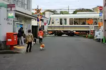 Japanische Stadtquartiere - ein JR-Zug der Serie 221 am Bahnübergang von Ôbaku an der Linie zwischen Kyoto und Nara. 7.April 2015. 