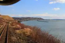 Hanasaki-Linie, Anfahrt auf das abgelegene Städtchen Akkeshi. Ueberall an der Pazifik-Küste verläuft die Strecke in sehr gefährdeter Lage; Sturm, Wellen oder gar Tsunami unterspülen oft die Geleise. Aus Triebwagen KIHA 54 523, 26.Oktober 2015.  
