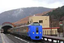 Intercity Triebwagenzug Serie 261 – Züge mit neigbarem Wagenkasten (elektronisch gesteuerte Regler füllen/entleeren die Luftfederbälge in Abhängigkeit der Fliehkräfte) stehen seit 2000 auf der Nordinsel Hokkaidô im Einsatz sowohl auf der Linie in den hohen Norden wie auf der Ost-West-Transversale bis zur Stadt Obihiro. Ihr Design wurde mit der dänischen DSB gemeinsam erarbeitet. Seit 2007 werden weitere neue Züge beschafft, und nachdem sich der Bau neuerer Typen wegen finanzieller und organisatorischer Probleme bei JR Hokkaidô zerschlagen hat, werden nun bis 2019 grössere Stückzahlen des Typs KIHA 261 nachgebaut, allerdings jetzt ohne Neigetechnik. Auf der Linie nach Obihiro verkehren die Züge als 5-Wagenzüge; mit Führerstand an einem Ende Serie KIHA 261, am andern Ende Serie KIRO 261 (Erstklasswagen), ohne Führerstand Serie KIHA 260, alle Wagen sind motorisiert. Zug KIRO 261-1103 in Tomamu, 28.Oktober 2015. Gut zu sehen ist der Schneeschutztunnel, der zu beiden Seiten der Station die Einfahrweichen schützt. SEKISHÔ-LINIE/NEMURO-HAUPTLINIE 