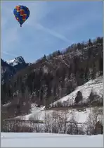 Ballon Festival 2016 Château d'Oex: Während der kaum zu sehende MOB Regionalzug 2222 von Montreux nach Zweisimmen in Kürze Rossinère erreichen wird. Schwebt ein Heissluftballon fast lautlos westwärts. 
26. Jan. 2016 