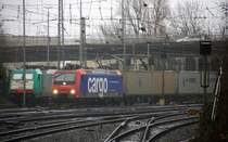 482 023-9 von SBB Cargo kommt aus Richtung Köln,Aachen-Hbf,Aachen-Schanz mit einem  Containerzug aus Novara(I) nach Genk-Zuid Haven(B) und fährt in Aachen-West ein. Aufgenommen vom Bahnsteig in Aachen-West. 
Bei Nieselregen und Sturm am Morgen vom 1.2.2016.