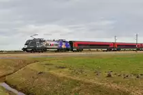 Die 1116 222-1 „The Red Bulletin“ der ÖBB vor einem Railjet am 09.02.16 bei Übersee am Chiemsee.