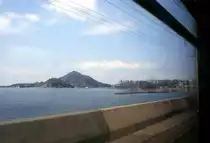Iyo-Bahn, auf der Takahama-Linie in Zug 714-764. Typische Strecke beim Hafen Takahama an der Inlandsee, dem Teil des Pazifischen Ozeans, der sich zwischen Shikoku und der japanischen Hauptinsel Honshû schiebt und für seine Tausenden von kleinen und kleinsten Inseln berühmt ist. Hier kommen die Fährschiffe von der Stadt Hiroshima an. 8. April 2008. 