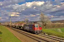 Am abend fährt die Re 4/4 II 421 390-6 bei einer von Saharastaub geprägten Wolkenstimmung in Umiken mit einem Mineralölzug vorbei.Bild vom 9.4.2016
