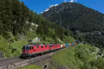 Re 4/4-11263 und Re 6/6-11627 fahren mit einem bunten Kieszug auf der dritten Ebene bei Wassen in Richtung Göschenen, aufgenommen am 25. Mai 2016.