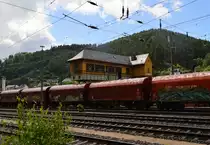 Eine fast unendlich scheinende Reihe von Tragwagen mit Plane stehen vor dem alten Reiterstellwerk des Bahnhof Finnentrop,2.7.2016