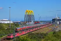 Abgestellte E-Loks und Reisezugwagen im Fährhafen Mukran. Im Hintergrund Jacket-Konstruktion für ein Offshore Park in der Ostsee. 19.07.2016