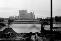 Wien am 31. Oktober 1976: Auf dem Bild sieht man links die Straßenbahnnotbrücke, die von der Gemeinde Wien und dem österreichischen Bundesheer als Ersatz für die am 1. August 1976 in die Donau eingestürzte Reichsbrücke errichtet worden war. - Auf der anderen Seite der Donau erkennt man eine E1+c2/c3-Garnitur auf einer der Donaustadtlinien (B, BK, 25 oder 26). Dieser Zug hat die Notbrücke eben benutzt. - Rechts im Bild befinden sich einige Reste der Reichsbrücke. - Zu der Zeit war die UNO-City in der Donaustadt noch im Bau. - Scan von einem S/W-Negativ. Film: Ilford FP 4. Kamera: Minolta SRT-101.