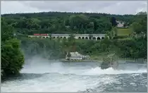 Zwei Re 4/4 II mit dem IC 181 (Stuttgart -Zürich) bei Neuhausen, im Vordergrund stürzt stiebend der Rhein über die Felsen.
Die Aufnahmen entstand in der Nähe des Schloss Laufen am Rheinfall am 18. Juni 2016.
