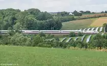 Gleicher Standpunkt wie #985912 am Hang des Ickbachtals: Hinter dem ICE liegt nicht sichtbar die Autobahn A7 und dahinter das kleine Dorf Unterickelsheim, von dem ein paar Häuser hervorspitzen. 