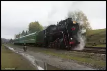 L 3535 wartet im Bahnhof Voronenko auf eine Überholung durch einen anderen Zug.
Während dessen fährt ein Motorrad Fahrer auf der vorbeiführenden Dorfstraße an dem Zug entlang.